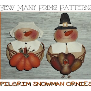 Op de afbeelding: Twee vilten pelgrim-sneeuwman ornamenten, een met een pompoen en de andere met een kalkoen. De ornamenten zijn wit met rode wangen en zwarte ogen. De tekst "Sew Many Prims Patterns" staat bovenaan de afbeelding en "Pilgrim Snowman Ornies" staat onderaan.