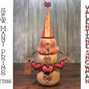 May include: A Valentine's Day snowman with a red and white hat that says "I Love You" and a garland of red hearts. The snowman is holding a sign that says "Monogrammed Towel & Bath Set" and "Feb 14 2023".