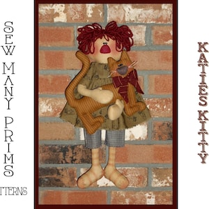 May include: A handmade rag doll with red hair and a brown and white striped dress holds a brown and white striped cat doll. The doll is standing on a brick wall. The text "Sew Many Prims Patterns" is on the left side of the image and "Katies Kitty" is on the right side of the image.