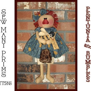 May include: A handmade rag doll with red hair and a blue and white dress. The doll is holding a bee with a yellow and black striped body. The doll is standing in front of a brick wall. The text "Bumble Bee" is on the doll's dress.