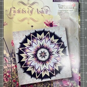 May include: A square, patterned fabric piece with a floral design in shades of purple, cream, and black, sits atop a magazine titled "Fields of Aster." The magazine features a woman and flowers. The text "Timeless Treasures" is visible.
