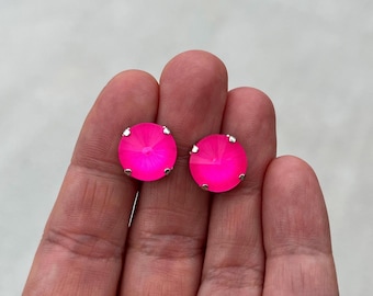 Puede incluir: Un par de pendientes de botón redondos de color rosa con engastes plateados.
