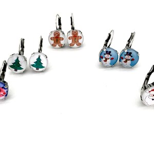 May include: Assortment of Christmas themed earrings with various designs including a snowman, Santa Claus, a gingerbread man, a Christmas tree, and a reindeer. The earrings are silver with a round glass charm.