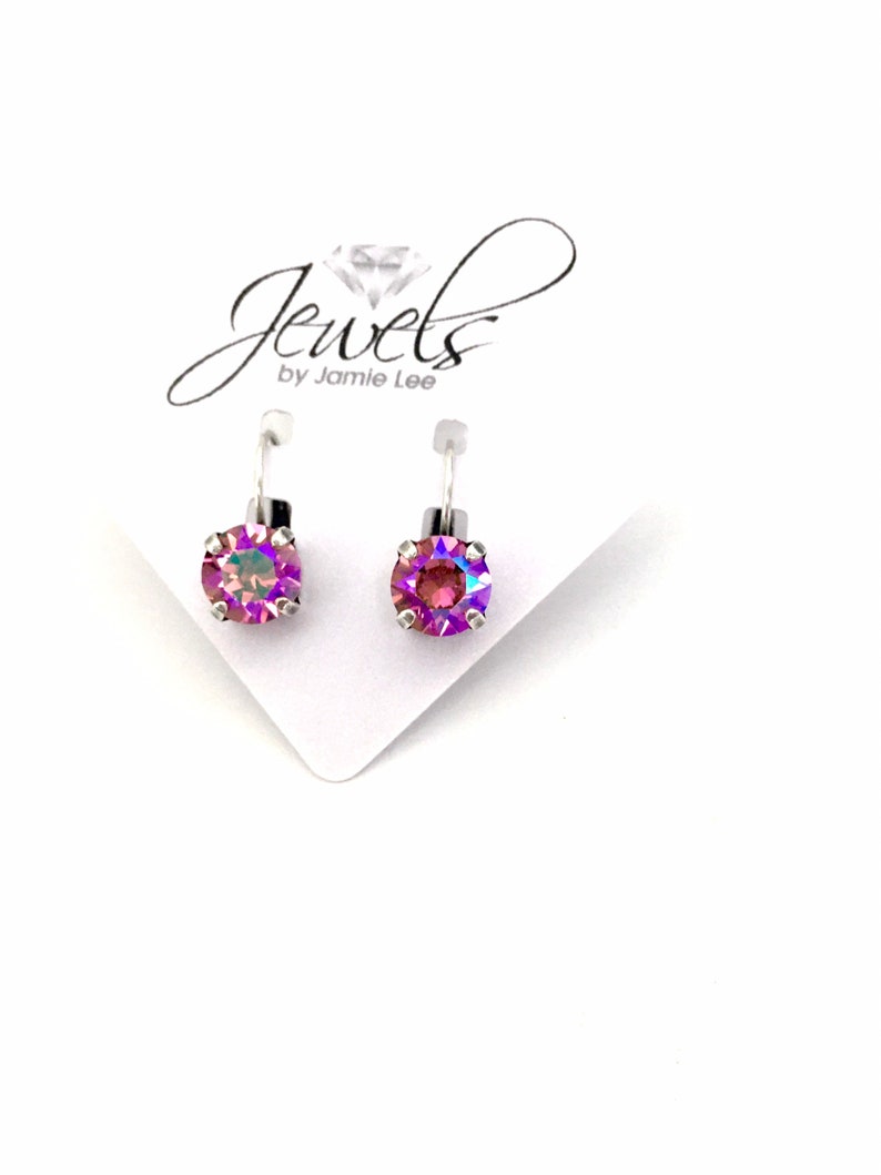 May include: A pair of silver earrings with iridescent purple gemstones. The earrings are on a white card with the text "Jewels by Jamie Lee".