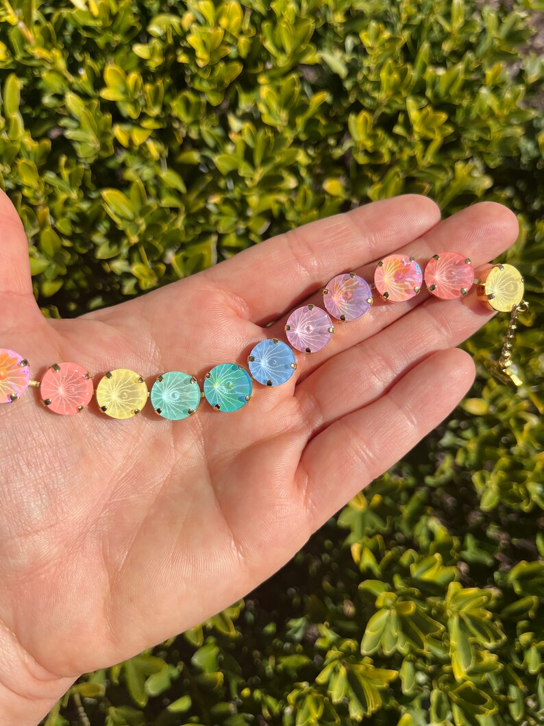 Peut inclure: Un bracelet en cristal arc-en-ciel avec des pierres rondes et iris&eacute;es. Le bracelet est en m&eacute;tal dor&eacute; et se ferme avec un fermoir.