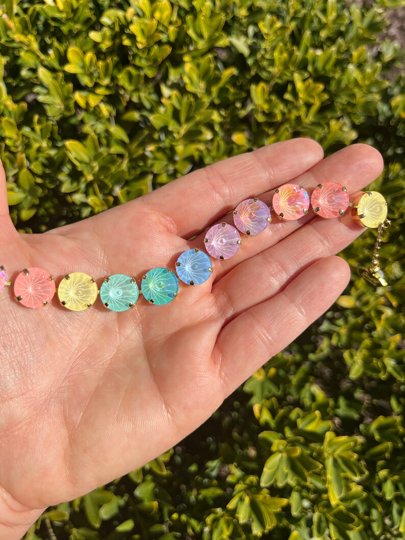 Peut inclure: Un bracelet en cristal arc-en-ciel avec des accents dor&eacute;s. Le bracelet pr&eacute;sente des cristaux ronds et iris&eacute;s dans des tons de rose, jaune, vert et bleu.