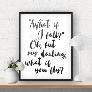 May include: Black and white typography print with the quote "What if I fall? Oh, but my darling, what if you fly?" framed in a black frame and displayed on a wooden table with a white lamp and a white vase with white flowers.