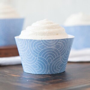 May include: Blue and white cupcake wrappers with a geometric pattern. The wrappers are made of paper and have a scalloped edge.