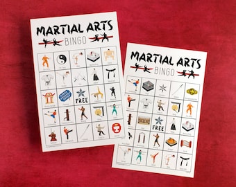 May include: Two white Martial Arts Bingo cards with illustrations of martial arts techniques and equipment. The cards have the words "MARTIAL ARTS BINGO" at the top. The background is a solid red.