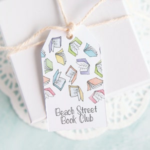 May include: A white gift tag with a colourful pattern of open books and the text "Beach Street Book Club".