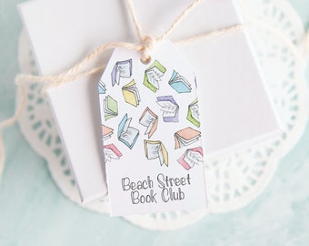 May include: A white gift tag with a colorful pattern of open books and the text "Beach Street Book Club".