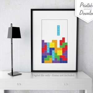 Peut inclure: Impression num&eacute;rique imprimable d'un jeu de Tetris en cours. Le jeu est compos&eacute; de blocs color&eacute;s dans des tons de rouge, orange, jaune, vert, bleu, violet et turquoise. L'impression est encadr&eacute;e dans un cadre noir et est affich&eacute;e sur une table blanche.