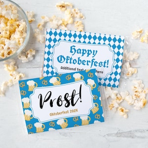 Peut inclure: Deux sachets de collation emballés dans du cellophane avec des motifs sur le thème de l'Oktoberfest. L'un présente un motif de losanges bleus et blancs avec le texte "Happy Oktoberfest!". L'autre a un fond bleu avec des chopes de bière et des bretzels, et le mot "Prost!"
