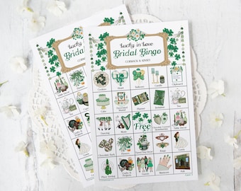 May include: A green and gold bridal bingo card with shamrock and heart designs. The card has a free space and squares with images of wedding-related items like cake, flowers, and a decorated mantel.