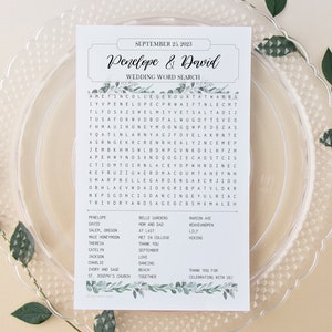 Könnte beinhalten: Ein Hochzeit-Wortsuchspiel mit grünem Blumenmuster. Das Spiel zeigt die Namen Penelope und David sowie das Datum 25. September 2023. Die Wortsuche enthält Wörter wie "Liebe", "Tanzen", "Strand" und "zusammen".