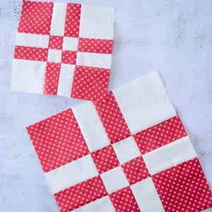 Könnte beinhalten: Zwei quadratische Quiltblöcke mit einem rot-weißen Muster. Der rote Stoff hat ein kleines sternförmiges Design. Die Blöcke sind diagonal angeordnet und zeigen das Patchwork-Design. Die Blöcke sind wahrscheinlich Teil eines größeren Quiltprojekts.