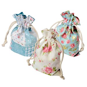 Puede incluir: Tres bolsas con cordón y estampados florales. Una es azul claro con flores blancas y rosas, otra es blanca con rosas rosas y la tercera es azul claro con rosas rosas. Cada bolsa tiene un cierre de cordón beige.