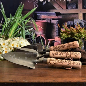 set of three garden tools with wooden handles and steel tops, a fork, a trowel a planter, hand engraved in a calligraphy font with the words If Nannys were flowers...Weed definitely pick you! Love Maddie & Lottie xx or choose your own messages