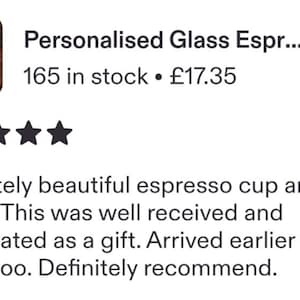 May include: A clear glass espresso cup and matching saucer set. The cup features white etched text that reads "Dad's Espresso" on the front. The set is filled with dark brown coffee and is positioned on a dark surface with scattered coffee beans.