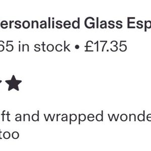 May include: A clear glass espresso cup and matching saucer filled with dark coffee. The glass features white text that reads Dad's Espresso. The set is displayed with scattered roasted coffee beans on a dark wooden surface.