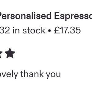 May include: A clear glass espresso cup featuring the word espresso printed in white script lettering on the front. The cup sits on a matching glass saucer, and a small wooden sign with the text for Mum is visible in the background.