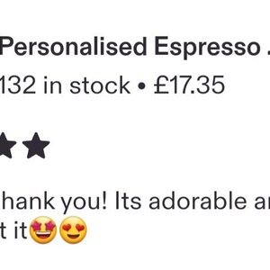 May include: A clear glass espresso cup featuring the word espresso in black cursive script, resting on a matching glass saucer. Next to the cup is a small wooden sign with the text for Mum and a small heart symbol, with a blurred background.