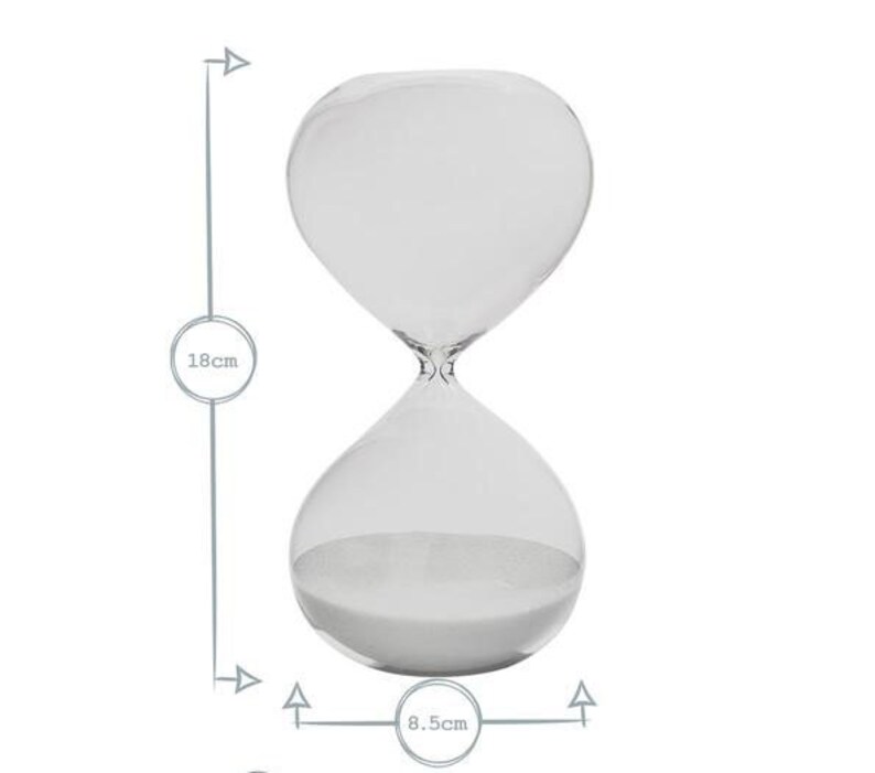 May include: A clear glass hourglass with white sand inside. The hourglass is 18 cm tall and 8.5 cm wide. The design is simple and elegant, suitable for home decor or as a functional timer.