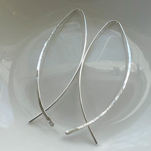 May include: A pair of silver hoop earrings with a hammered texture. The earrings are simple and elegant, and would make a great gift for any occasion.