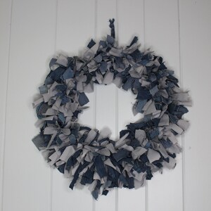 May include: A wreath made of blue and gray fabric scraps. The wreath is circular and has a rustic, handmade look.