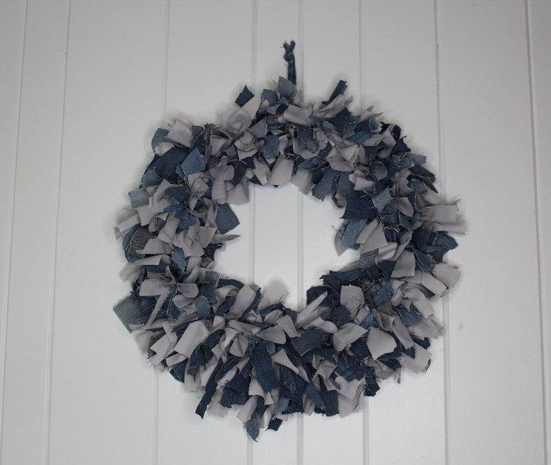 May include: A wreath made of blue and gray fabric scraps. The wreath is circular and has a rustic, handmade look.