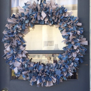 May include: A wreath made of blue denim and gray fabric scraps. The wreath is hanging on a door.