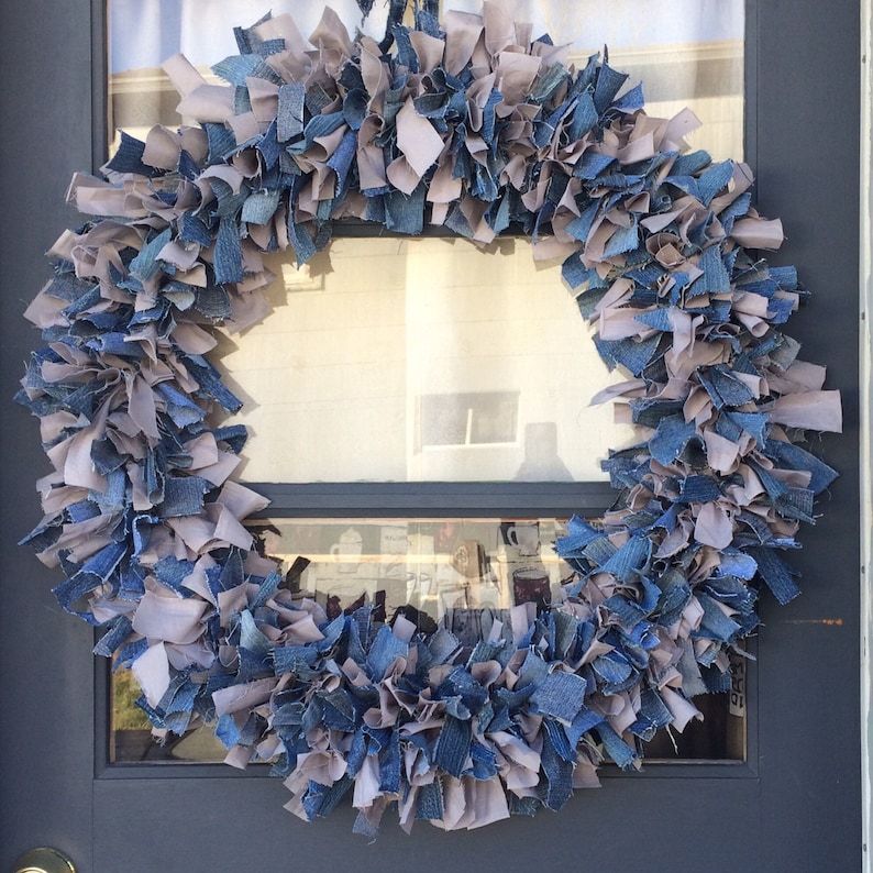 May include: A wreath made of blue denim and gray fabric scraps. The wreath is hanging on a door.