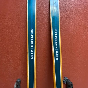 May include: A pair of vintage wooden skis with blue and white stripes and the text "SPLITKEIN | BASS" printed on them.