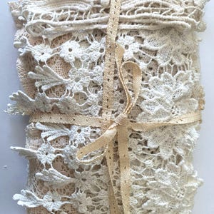 Puede incluir: Un paquete de encaje color crema, con intrincados dise&ntilde;os florales. El encaje est&aacute; atado con una cinta beige, creando un paquete ordenado. La delicada textura y los tonos neutros sugieren un art&iacute;culo artesanal vintage, ideal para proyectos.