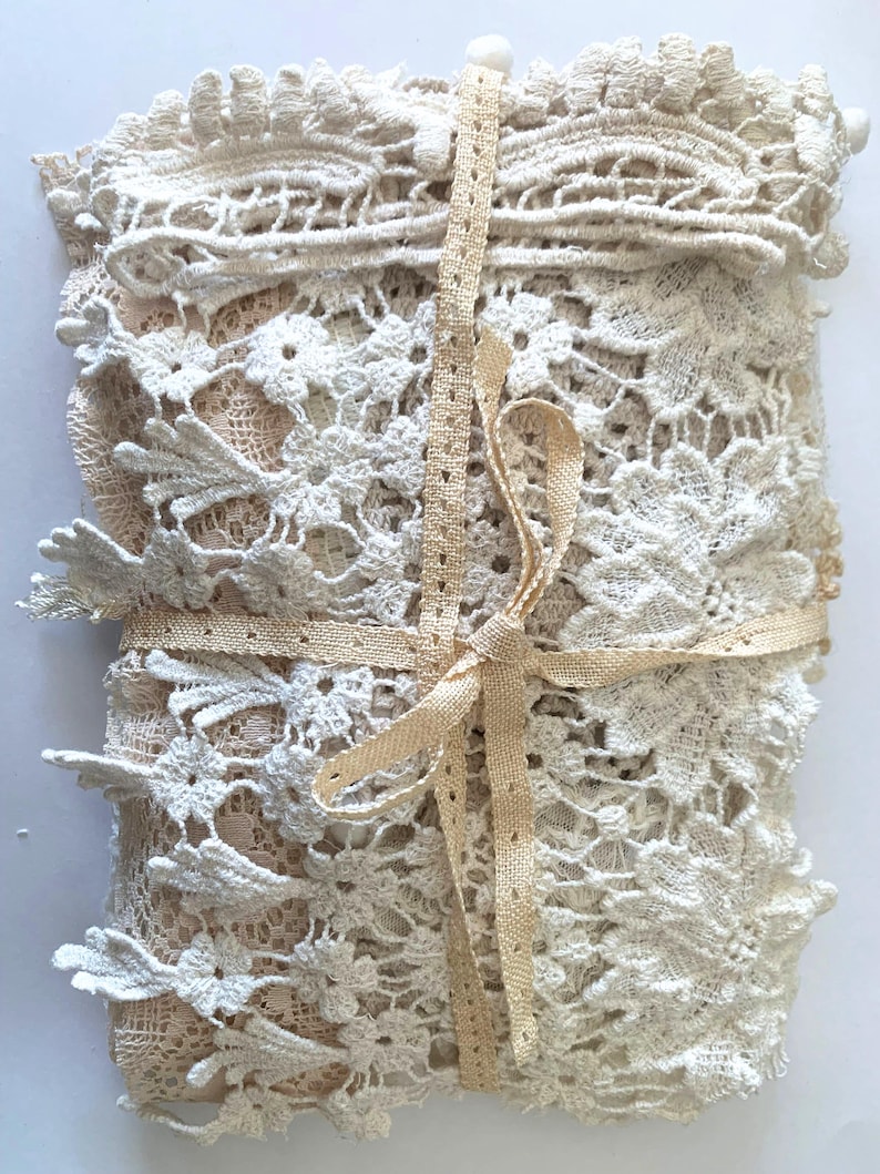 Puede incluir: Un paquete de encaje color crema, con intrincados dise&ntilde;os florales. El encaje est&aacute; atado con una cinta beige, creando un paquete ordenado. La delicada textura y los tonos neutros sugieren un art&iacute;culo artesanal vintage, ideal para proyectos.