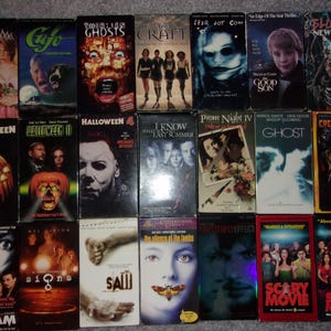 May include: A collection of 20 VHS tapes featuring horror movie titles such as "Scream", "Halloween", "The Craft", "Ghost", "I Know What You Did Last Summer", "Prom Night", "Signs", "Saw", "The Silence of the Lambs", "Scary Movie", and "Bloody New Year".