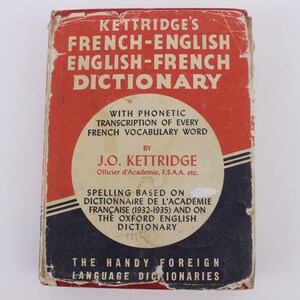 May include: A red and blue book cover with the title "Kettrdige's French-English English-French Dictionary". The book includes phonetic transcription of every French vocabulary word and is based on the Dictionnaire de l'Académie Française and the Oxford English Dictionary.