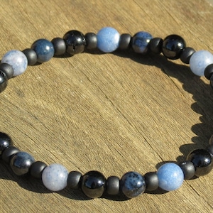 May include: A beaded bracelet with alternating black and blue beads. The blue beads are a mix of light and dark blue.