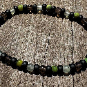 May include: A beaded bracelet with black, green and brown beads.