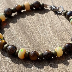 May include: A brown and gold beaded bracelet with opal accents. The bracelet has a silver clasp.