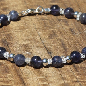 Può includere: Un braccialetto d'argento con perline blu scuro e trasparenti. Il braccialetto ha una chiusura in argento.