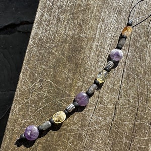 May include: A purple, yellow, and gray beaded phone charm with a black cord.