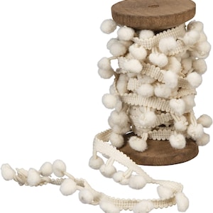 May include: A spool of white pom-pom trim with a wooden base. The trim is made of soft, fluffy pom-poms and a delicate white ribbon.