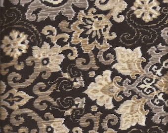 May include: Close-up of a patterned fabric with a dark brown background and floral designs in shades of beige, tan, and gray. The fabric has a textured appearance, with a quarter coin for scale.