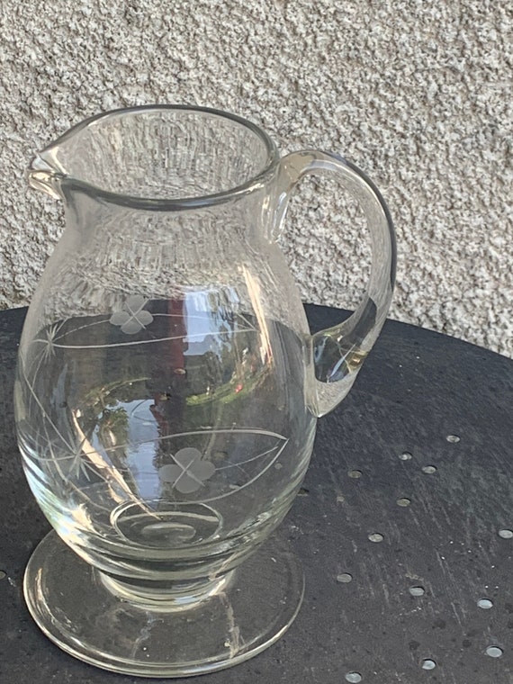 Transparent glass carafe with a pattern of foliage and carved clovers, vintage,
