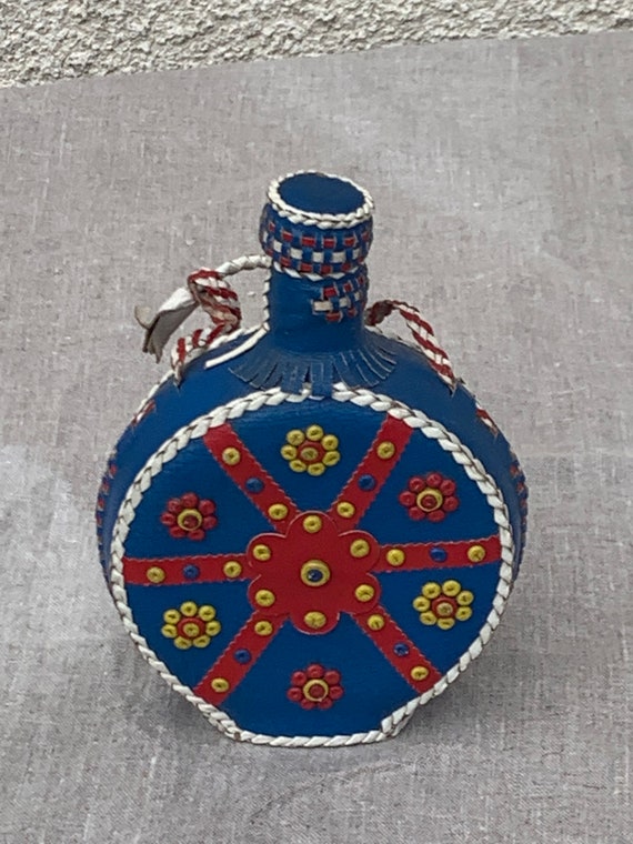 Bottle, ocher glass bottle dressed in blue and red leather with vintage patterns