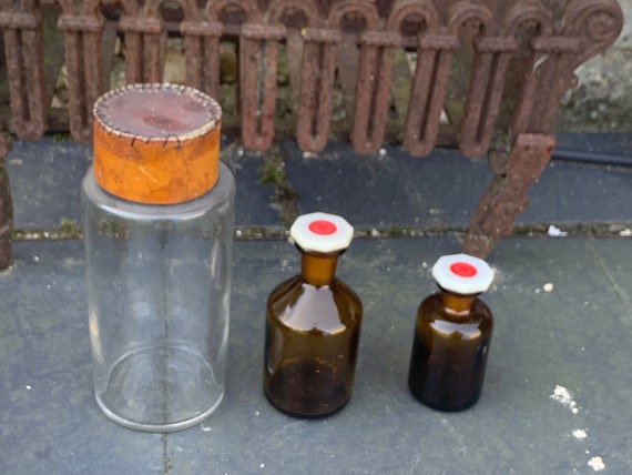 Lot of 3 apothecary bottles, vials, one large with hand-sewn cap, Herbalism, transparent glass and two in amber glass and bakelite cap, old