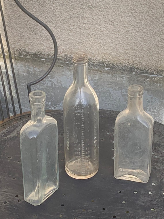 3 old bottles, for syrups, medicines, composed of a graduated bottle in relief, grams, and two Marinol bottles, art deco,