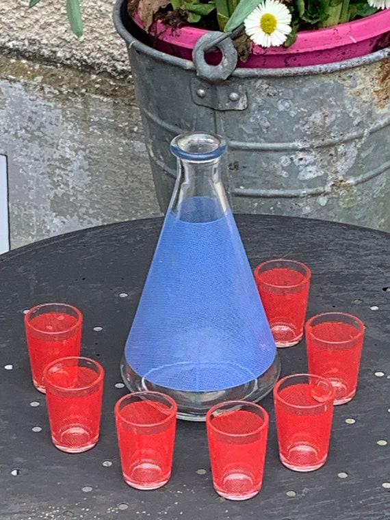 Liqueur service composed of a blue screen-printed glass carafe and 7 small red glasses with mesh fabric effect BVB France vintage 1960