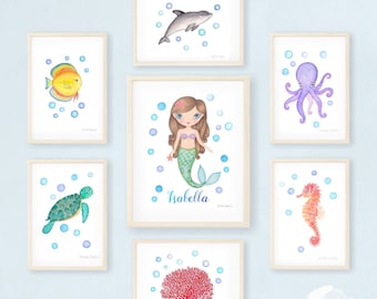 May include: A set of eight watercolor prints featuring various sea creatures, including a dolphin, a fish, a mermaid, an octopus, a sea turtle, a seahorse, and coral. The prints are framed in light wood and have a white background with blue bubbles.